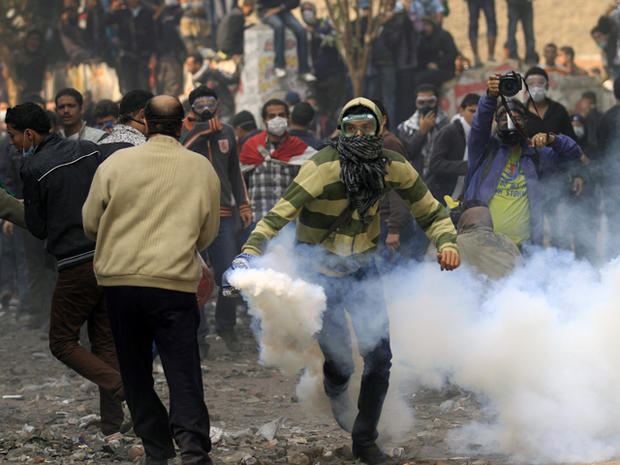 Protester runs to throw a tear gas canister 
