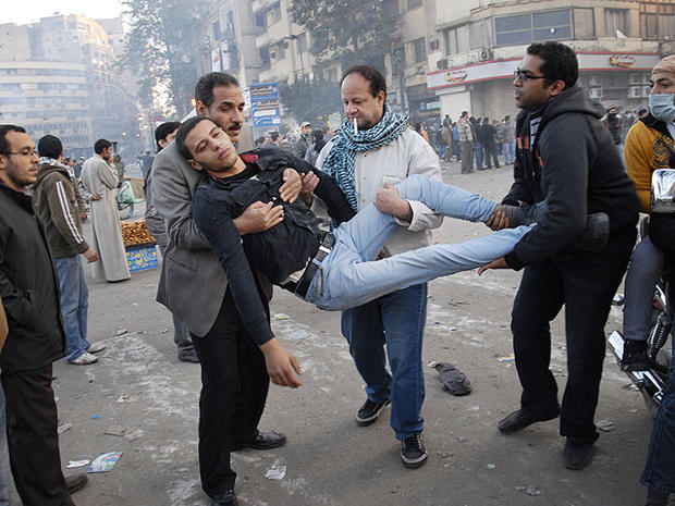 Egyptian men carry a wounded protester during clashes with Egyptian riot police, unseen, in Cairo, Egypt, Nov. 23, 2011. 