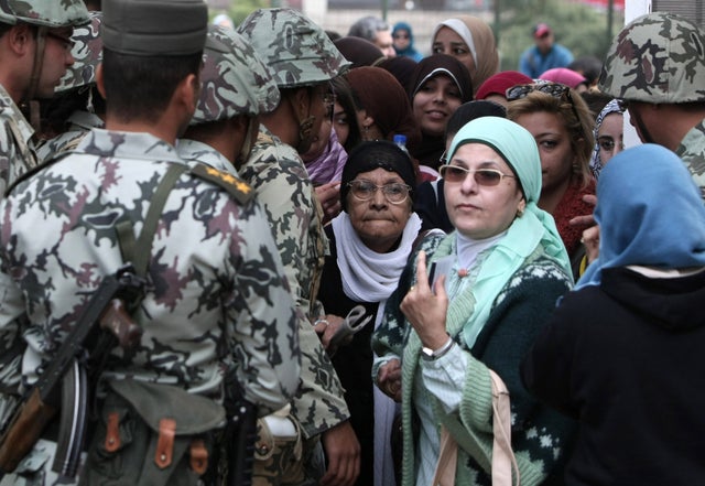 Egyptian women walk past soldiers as they arrive to vote 