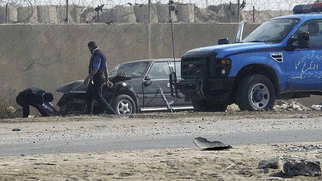 People prepare to tow away a car damaged by a suicide car bomb explosion in the town of Taji, about 12 miles north of Baghdad, Iraq, Nov. 28, 2011.  