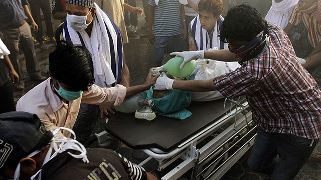 People help carry a patient out of a hospital after it caught fire in Kolkata, India, Dec. 9, 2011.  