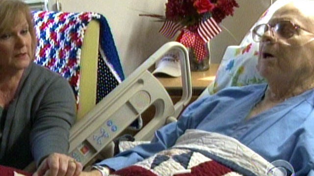 Barbara Stadler, a Veterans Affair employee who volunteers at the hospital's end-of-life program, holds the hand of Korean war vet Richard Murley. 