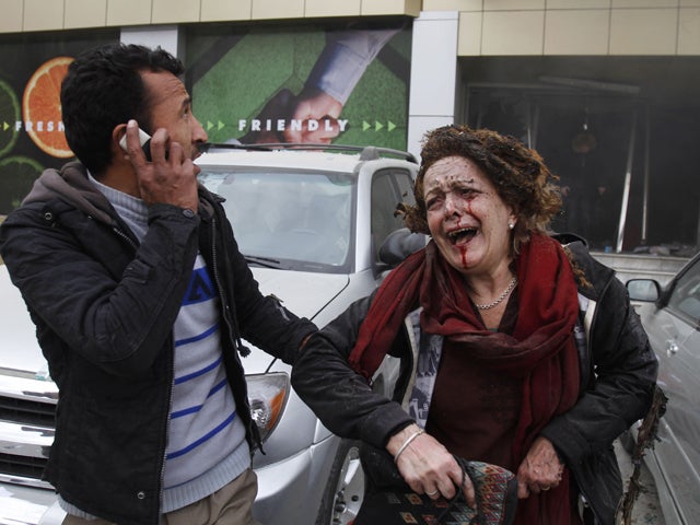 An injured woman is escorted out of a supermarket 