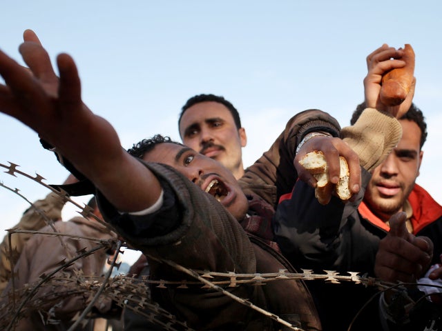 Men reach for bread behind barbed wire  