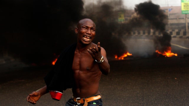 A angry youth protests in front of a burning barrier following the removal of a fuel subsidy by the government in Lagos, Nigeria, Jan. 10, 2012. Angry youths erected a burning roadblock outside luxury enclaves in Nigeria's commercial capital as a paralyzi 