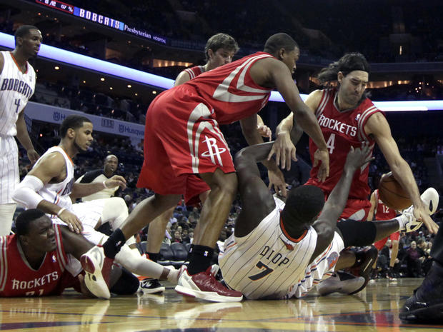 Houston Rockets' Luis Scola, right, and Kyle Lowry, second from right, battle with Charlotte Bobcats' DeSagana Diop (7) for control of a loose ball  