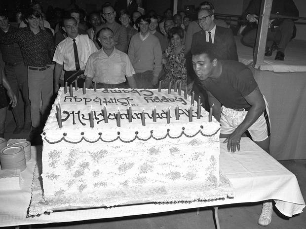 Muhammad Ali blows out the candles on a cake 