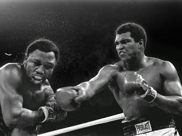 Sweat spray flies from the head of challenger Joe Frazier as Muhammad Ali connects 