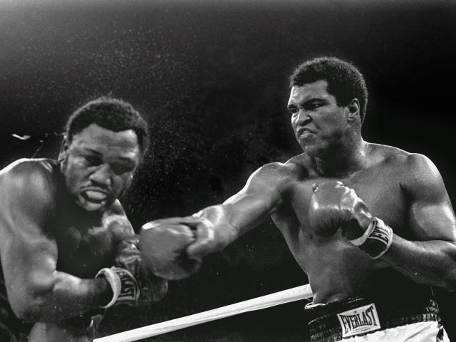 Sweat spray flies from the head of challenger Joe Frazier as Muhammad Ali connects  