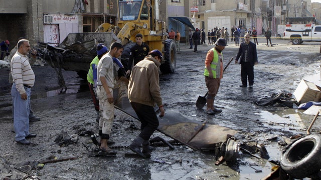 People clean the scene of a car bomb attack 