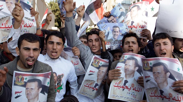 Protesters shout slogans as they carry pictures of Syrian President Bashar Assad and Syrian flags 