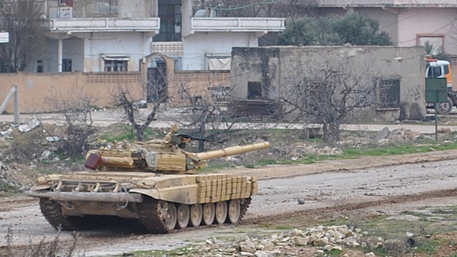 Syrian tank moves along a road during clashes with Syrian army defectors 
