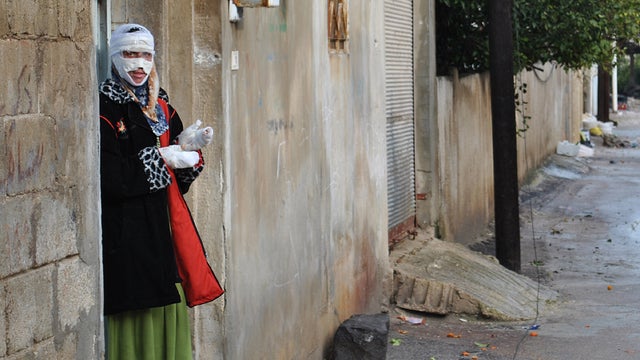 A woman wounded by mortar fire stands at her home in Rastan, Homs province 
