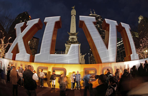  fans pose for photos in front of a sign for Super Bowl XLVI  