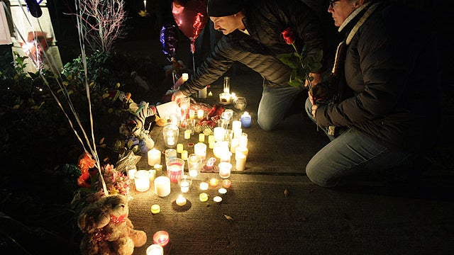 Mark and Pam Figliola place flowers and a card at a candle-light memorial for the two sons of Josh Powell and Susan Cox, Sunday, Feb. 5, 2012, at Carson Elementary School in Puyallup, Wash., where the older of the boys attended school.  