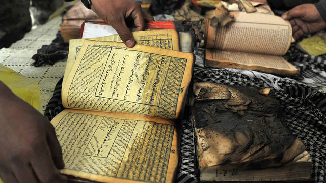 Afghan demonstrators show copies of Quran books allegedly set alight by US soldiers 