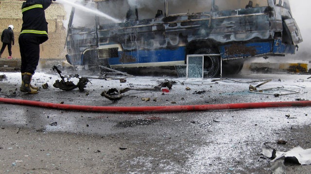 Iraqi firefighters try to extinguish a burning bus at the scene of a car bomb explosion 