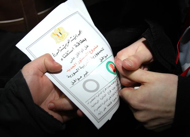 A Syrian citizen marks a ballot paper with her blood at a polling station during a referendum on the new constitution, in Damascus, Syria, on Sunday Feb. 26, 2012. 