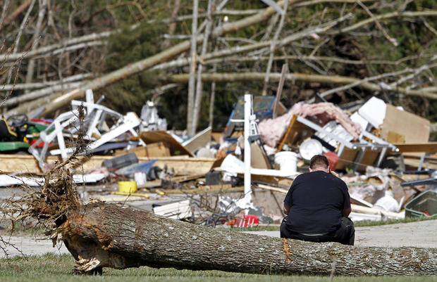 Mike Hatheway sits on a tree uprooted by a deadly tornado  