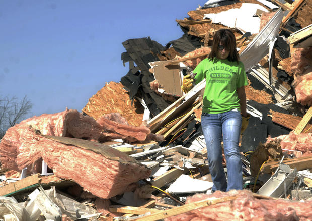 Kera Wise searches for items in the rubble of a house  