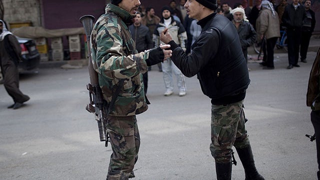 In this March 11, 2012 photo, Free Syrian Army fighters discuss military strategies during a day of fierce fighting with Syrian Army forces in Idlib, north Syria. 