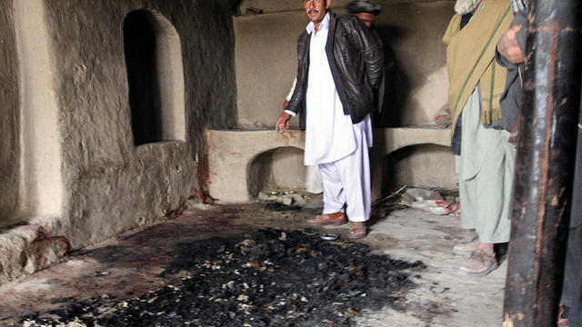 Men stand next to blood stains and charred remains inside a home where witnesses say Afghans were killed by a U.S. soldier 