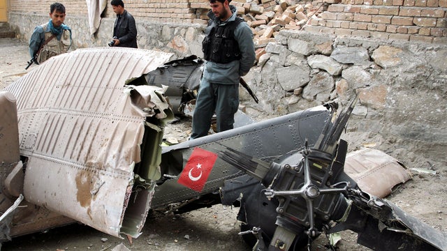 An Afghan policeman looks at the wreckage from a crashed Turkish helicopter on the outskirts of Kabul, Afghanistan, March 16, 2012. 