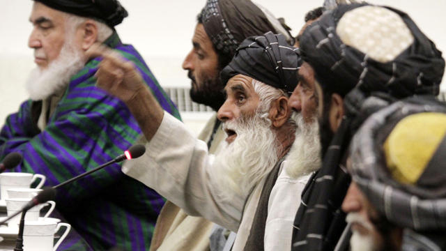 Abdul Samad, center, eleven of whose family members were allegedly killed by a U.S. soldier in Panjwai, Afghanistan, talks with Afghan President Hamid Karzai, unseen, at the presidential palace in Kabul, Afghanistan, March 16, 2012. 