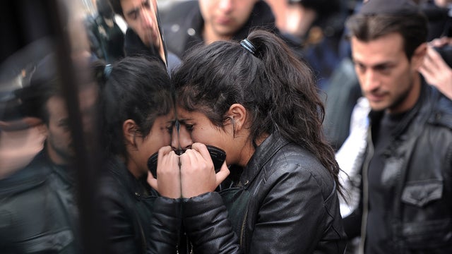 A woman cries as she stands against the side window of a convoy carrying coffins of the victims of a gun attack before it leaves the Ozar Hatorah Jewish school after a funeral ceremony March 20, 2012, in Toulouse, France. 