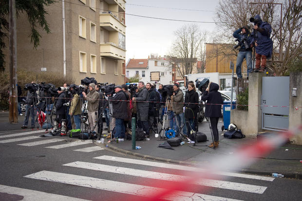 Journalists wait as French police officers and firefighters and members of the RAID special police forces unit contain the apartment block where Mohamed Merah, the man suspected of a series of deadly shootings, was holed up March 22, 2012, in Toulouse, Fr 