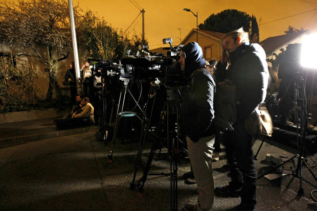 Journalists stand at night next to an apartment building where Mohamed Merah, a suspect in the shooting at the Ozar Hatorah Jewish school, is barricaded in Toulouse, France, March 22, 2012. 