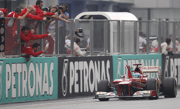 Fernando Alonso of Spain celebrates as he passes his team on the pit lane wall after winning the Malaysian Formula One Grand Prix  