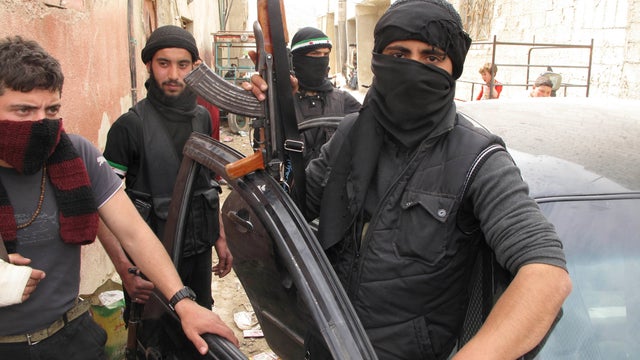 In this Sunday, April 1, 2012 photo, Free Syrian Army fighters are seen in a neighborhood of Damascus, Syria. Government and opposition forces clashed across Syria Monday as international envoy Kofi Annan prepared to brief the U.N. Security Council on the 