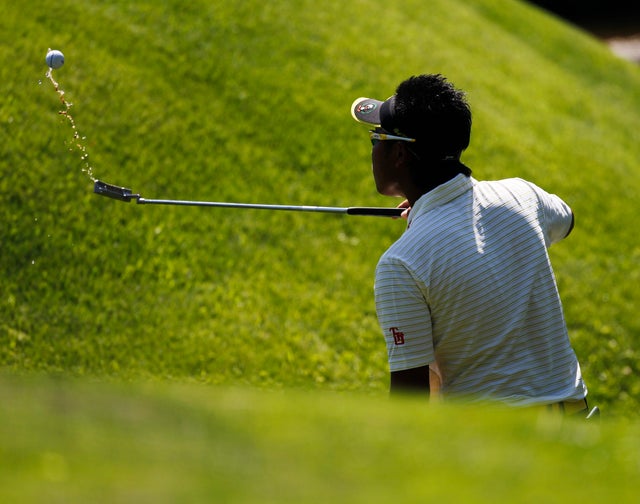 Hideki Matsuyama fishes his ball out of Rae's Creek on the 13th fairway  