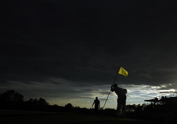 Peter Hanson, of Sweden's caddie Mark Sherwood holds a flag stick on the 18th hole 