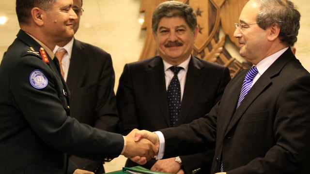 Gen. Abhijit Guha, left, deputy military adviser in the United Nations Department of Peacekeeping Operations, and Syrian Deputy Foreign Minister Faisal Meqdad shake hands in signing a preliminary accord April 19, 2012, in Damascus, Syria, outlining a prot 