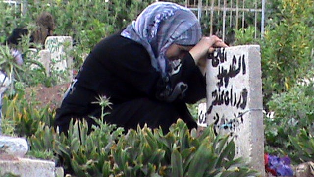 A Syrian woman mourns the death of a relative at a grave in the city of Rastan, Syria, just north of the central restive city of Homs, April 19, 2012. 