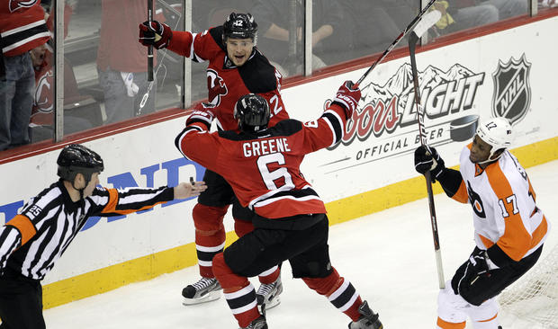 Official Marc Joannette, left, signals the goal as New Jersey Devils' Alexei Ponikarovsky (12) celebrates his game-winning score with teammate Andy Greene 