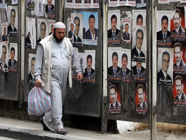 Syrian man walks past campaign posters for the upcoming parliamentary election 