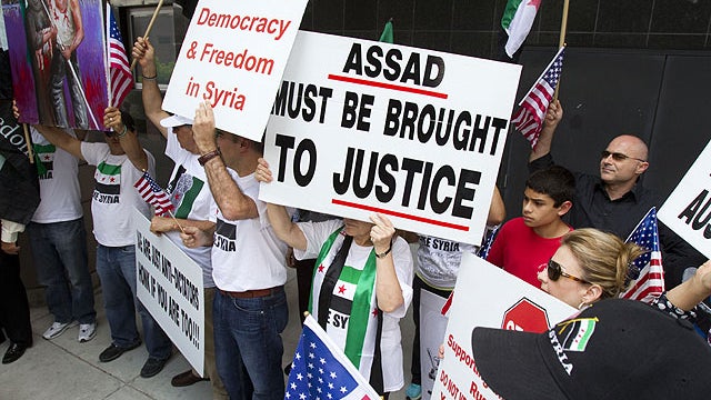 Demonstrators march outside the Bob Casey Federal Courthouse during a news conference condemning the Syrian government, May 29, 2012, in Houston.  