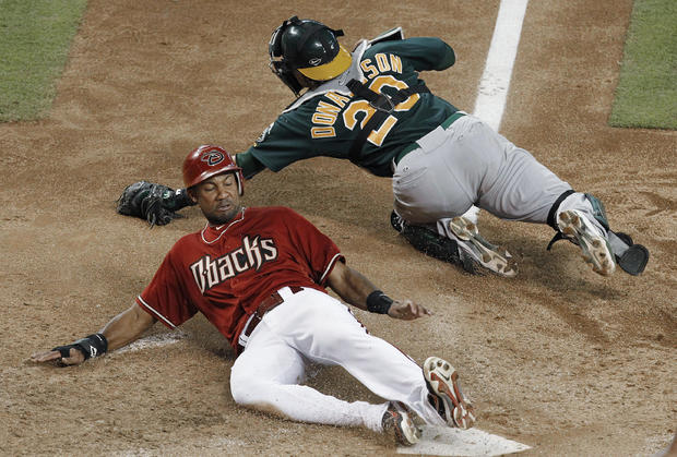 Chris Young slides in to score as Oakland Athletics' Josh Donaldson dives to catch a wide throw  
