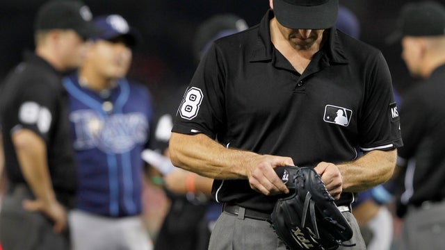 Umpire Chris Guccione leaves with the glove of Tampa Bay Rays relief pitcher Joel Peralta  