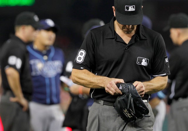 Umpire Chris Guccione leaves with the glove of Tampa Bay Rays relief pitcher Joel Peralta  