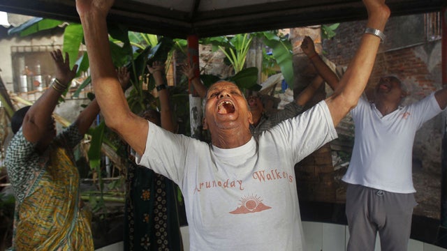 In this Friday, June 22, 2012 photo, members of the Sheetal Jogging Association perform laughter yoga around Sheetal Talao pond where they have been coming every morning for three years for laughter yoga, devotional singing and light exercise in Mumbai, I 