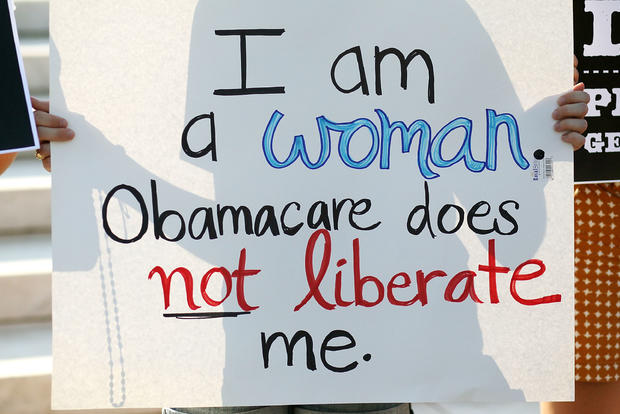 A woman holds a sign while protesting against the administration's health care act  