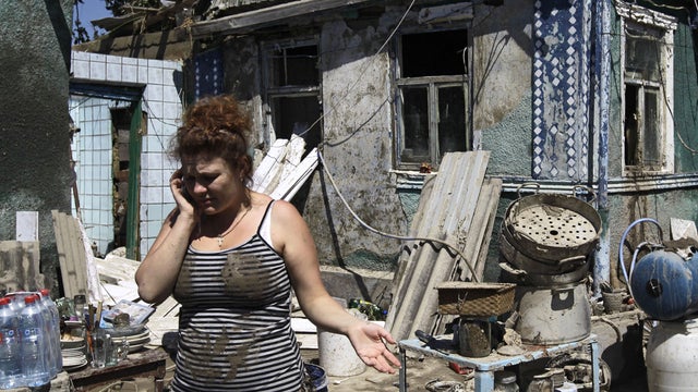 A woman speaks on a cell phone in front of her house damaged by flood water in the town of Nizhnebakansky, about 1,200 kilometers (750 miles) south of Moscow, Monday, July 9, 2012.  