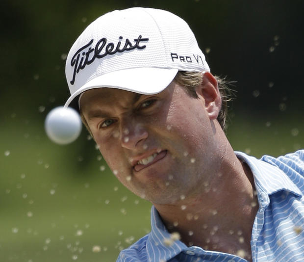 Webb Simpson watches the ball as he hits out of a bunker 