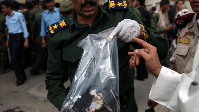 A Yemeni police officer holds evidence collected at the site of a suicide bombing at the entrance of a police academy in Sanaa, Yemen, July 11, 2012. 