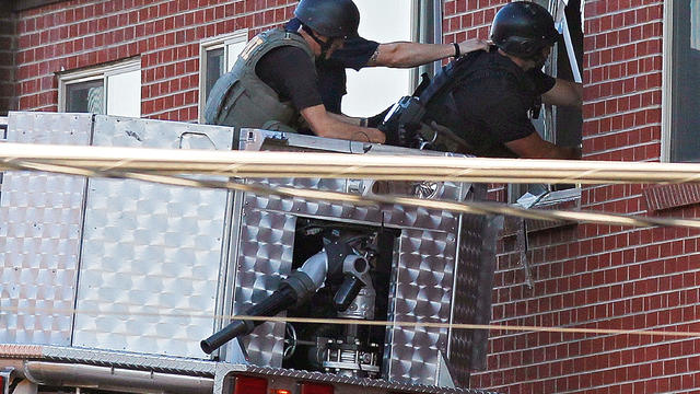 An Aurora Police officer talks on his radio outside of the Century 16 theater at Aurora Mall where as many as 14 people were killed and many injured at a shooting at the Century 16 movie theatre in Aurora, Colo., Friday, July 20, 2012.  
