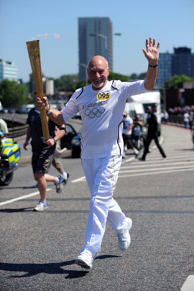 Patrick Stewart carries the Olympic Flame on the Torch Relay in London on July 23, 2012. 